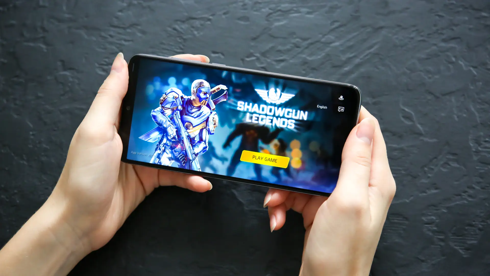 Uma pessoa está com o celular na horizontal. Na tela aparece um jogo