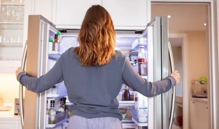 Mulher abrindo uma geladeira inox Side by Side.