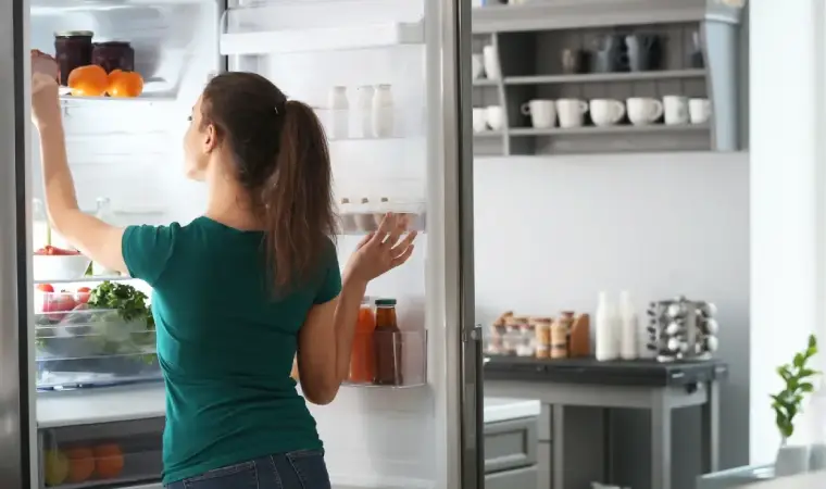 Imagem de uma mulher pegando um produto dentro da geladeira