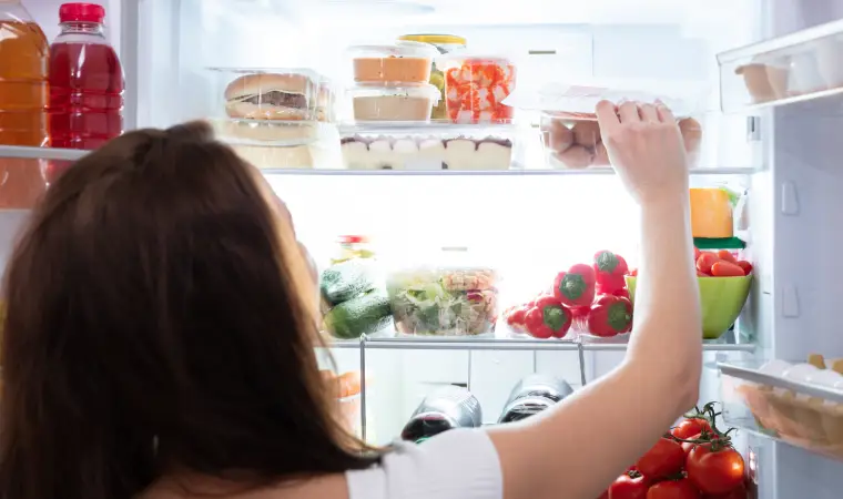 Mulher pegando alimentos dentro de uma geladeira Frost Free.