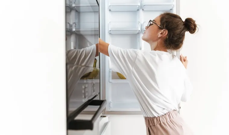 Mulher olhando uma geladeira Inverse aberta.
