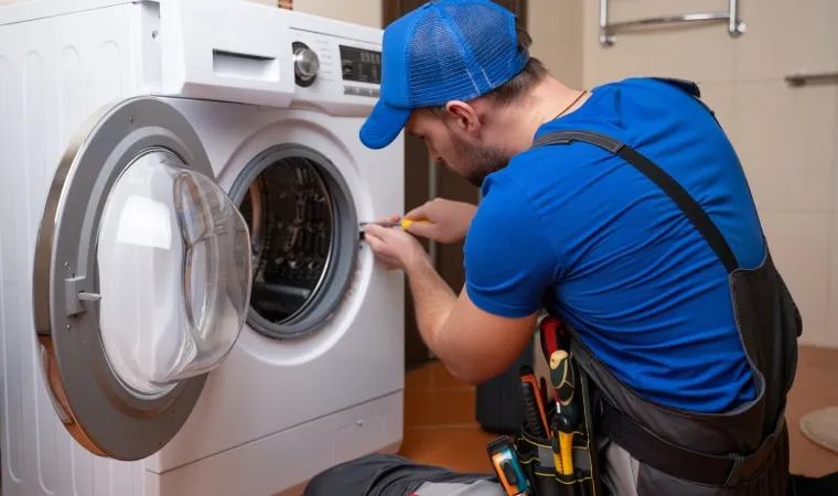Homem consertando a máquina de lavar.