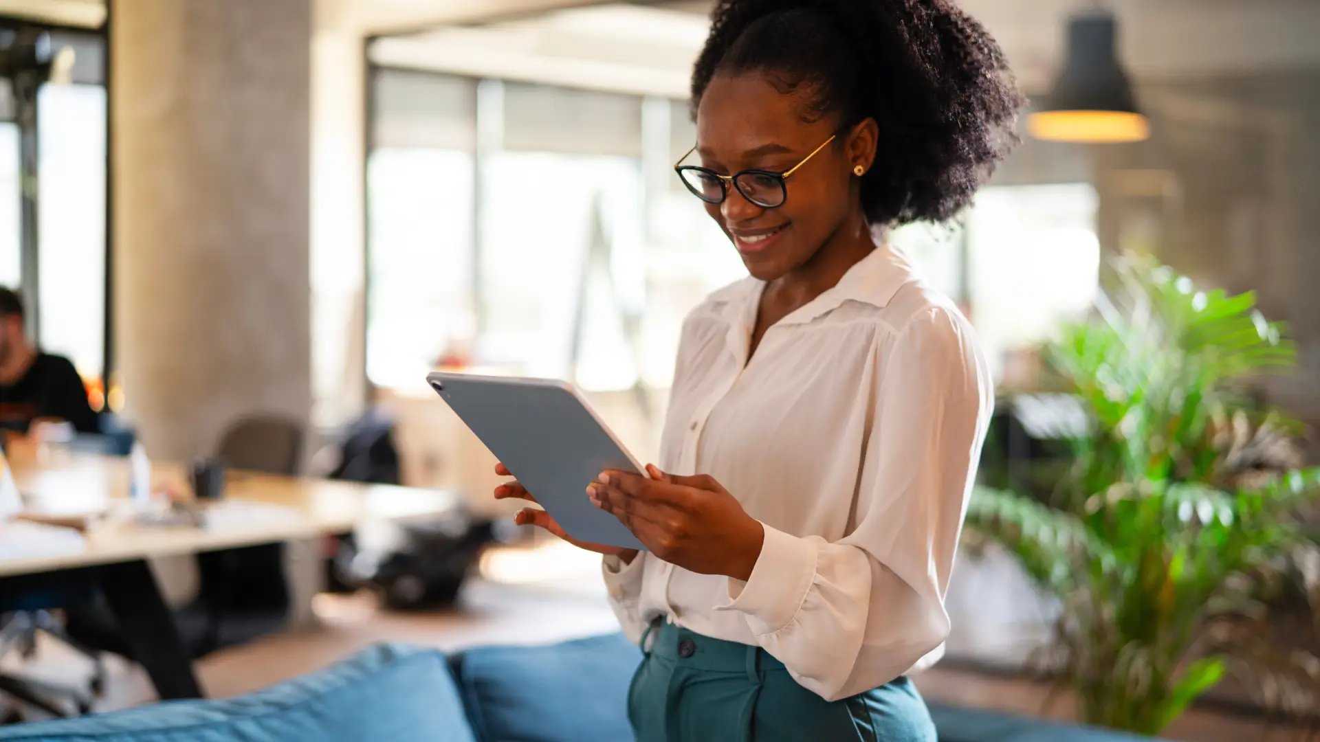 Uma mulher está de pé sorrindo enquanto olha a tela de um tablet