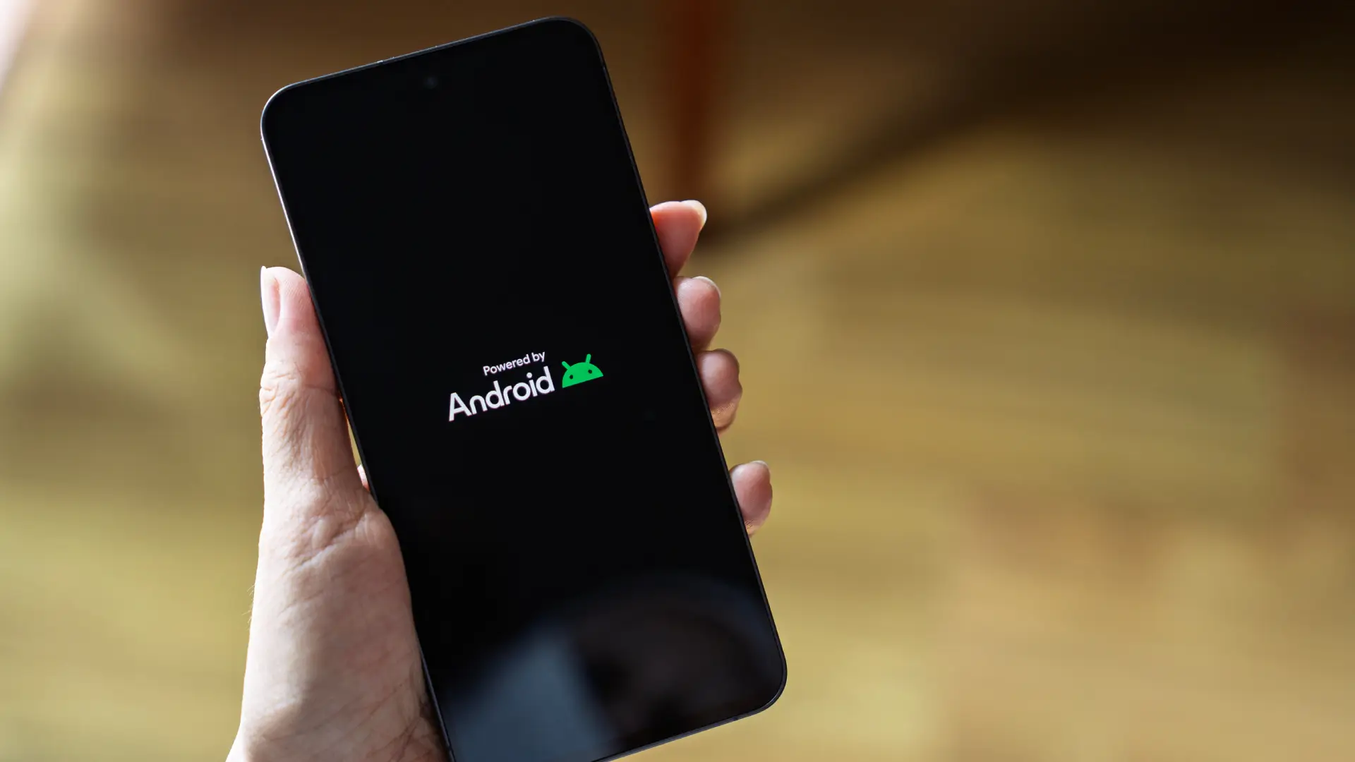 Imagem de uma pessoa segurando um celular com a logo do Android