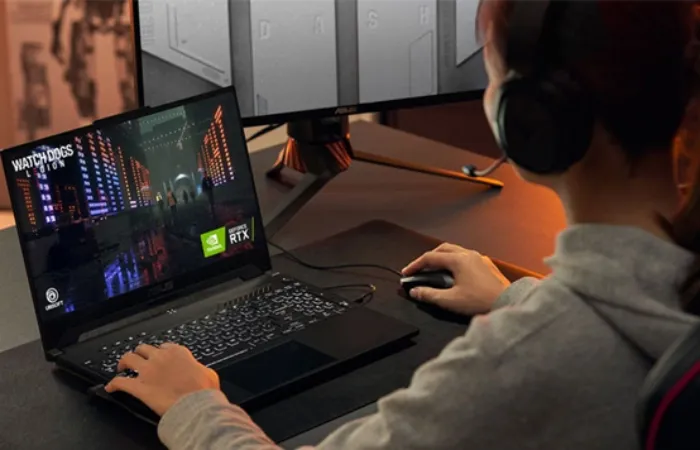 Pessoa usando o notebook ASUS TUF Dash F15 com uma mão no teclado e outra no mouse enquanto joga o game Watch Dogs