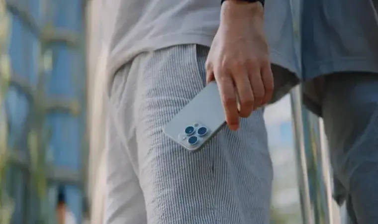Imagem de uma pessoa segurando um iPhone próximo ao bolso