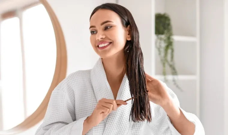 Jovem moça penteando o cabelo com o pente e sorrindo