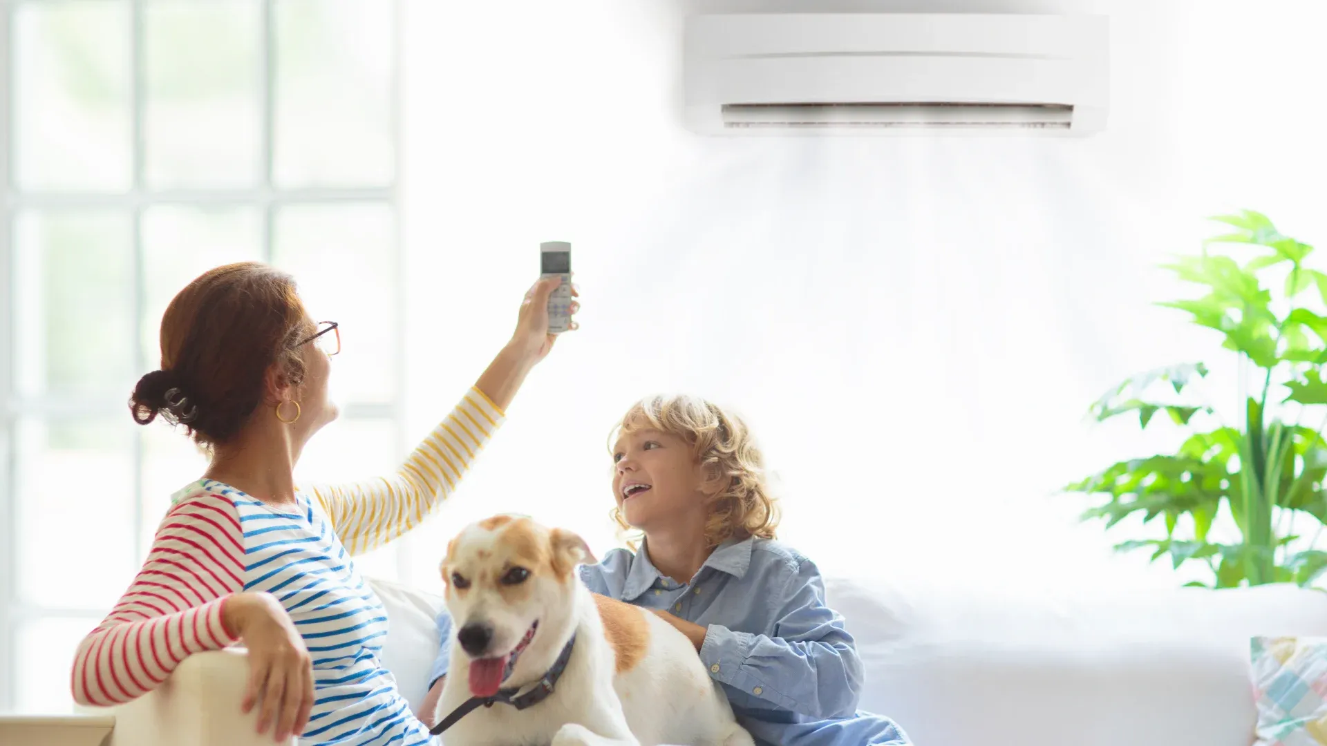 Mãe, filho e cachorro sentados no sofá aproveitando o ar-condicionado