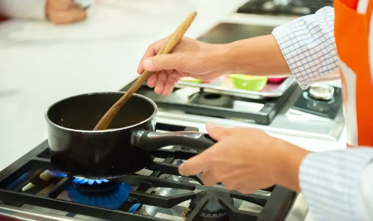Pessoa cozinhando em um fogão 4 bocas inox.