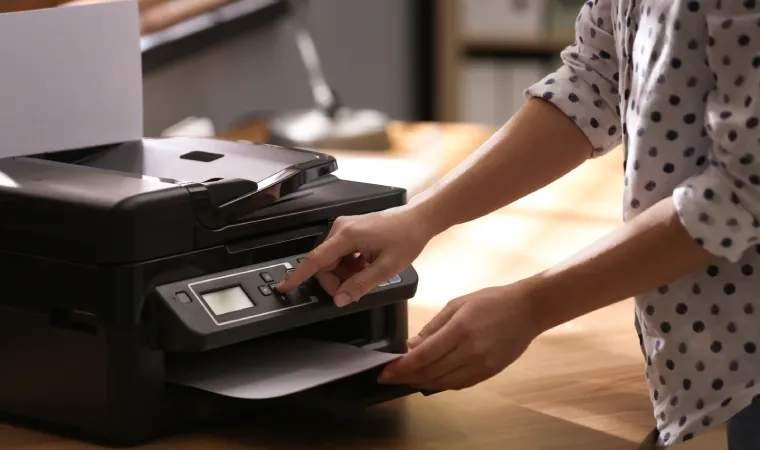 Mulher colocando folha de papel em uma mpressora preta.