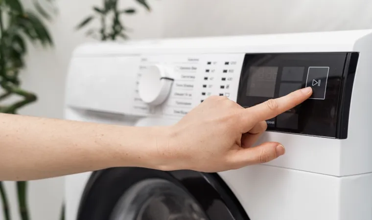 Pessoa apertando um botão em uma máquina lava e seca.