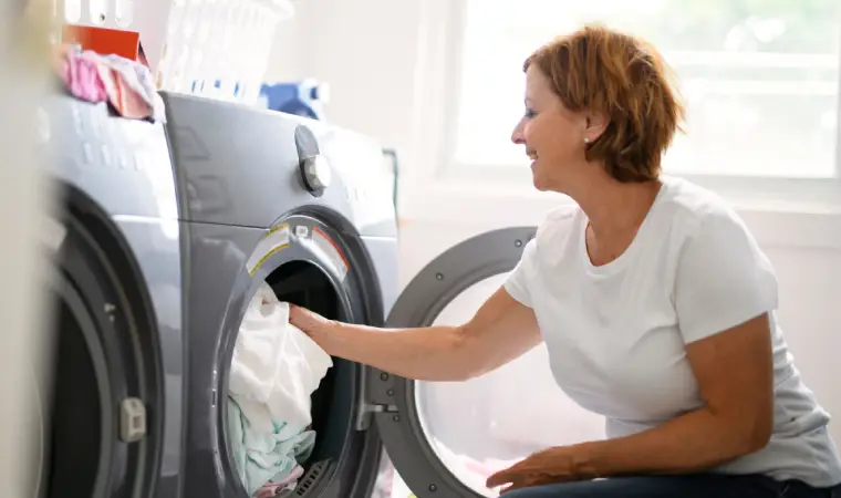 Mulher tirando roupas de dentro da lava e seca Samsung.