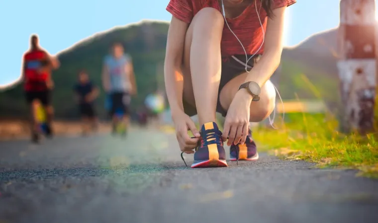 Mulher amarrando o cadarço do seu tênis de corrida.