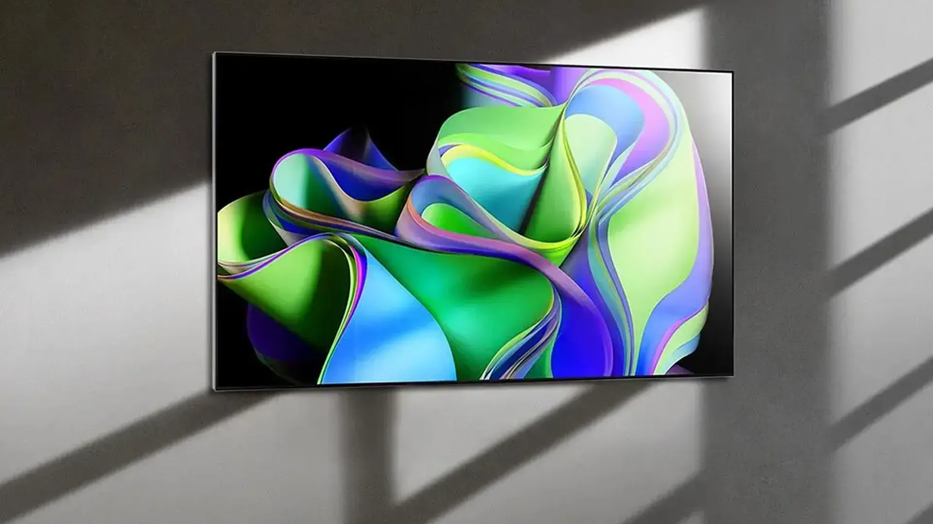 Imagem da LG OLED C3 montada na parede, mostrando o painel fino e a sombra projetada no fundo cinza