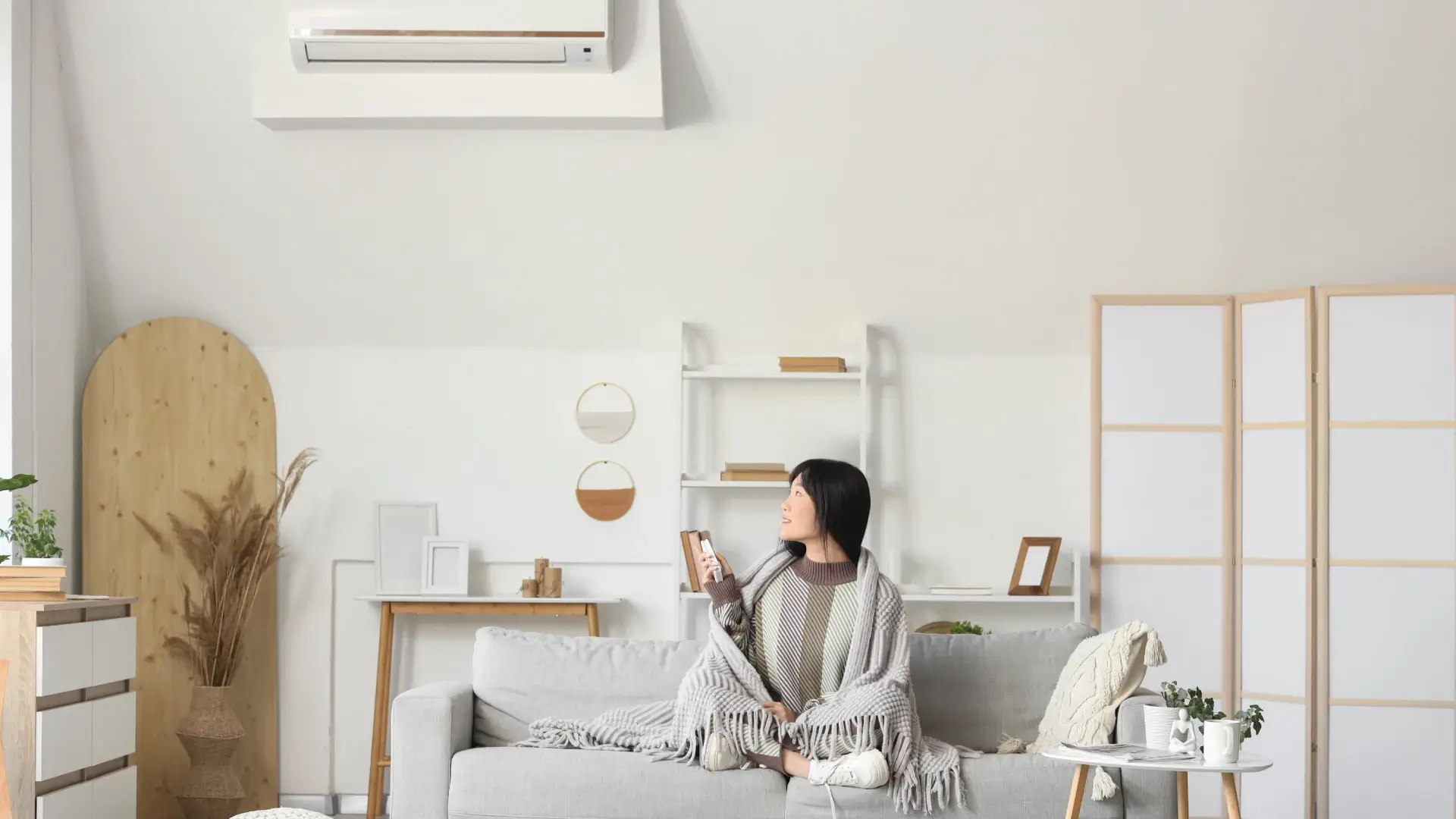 Imagem de uma mulher esquentando suas mãos com o ar-quente de um ar-condicionado 