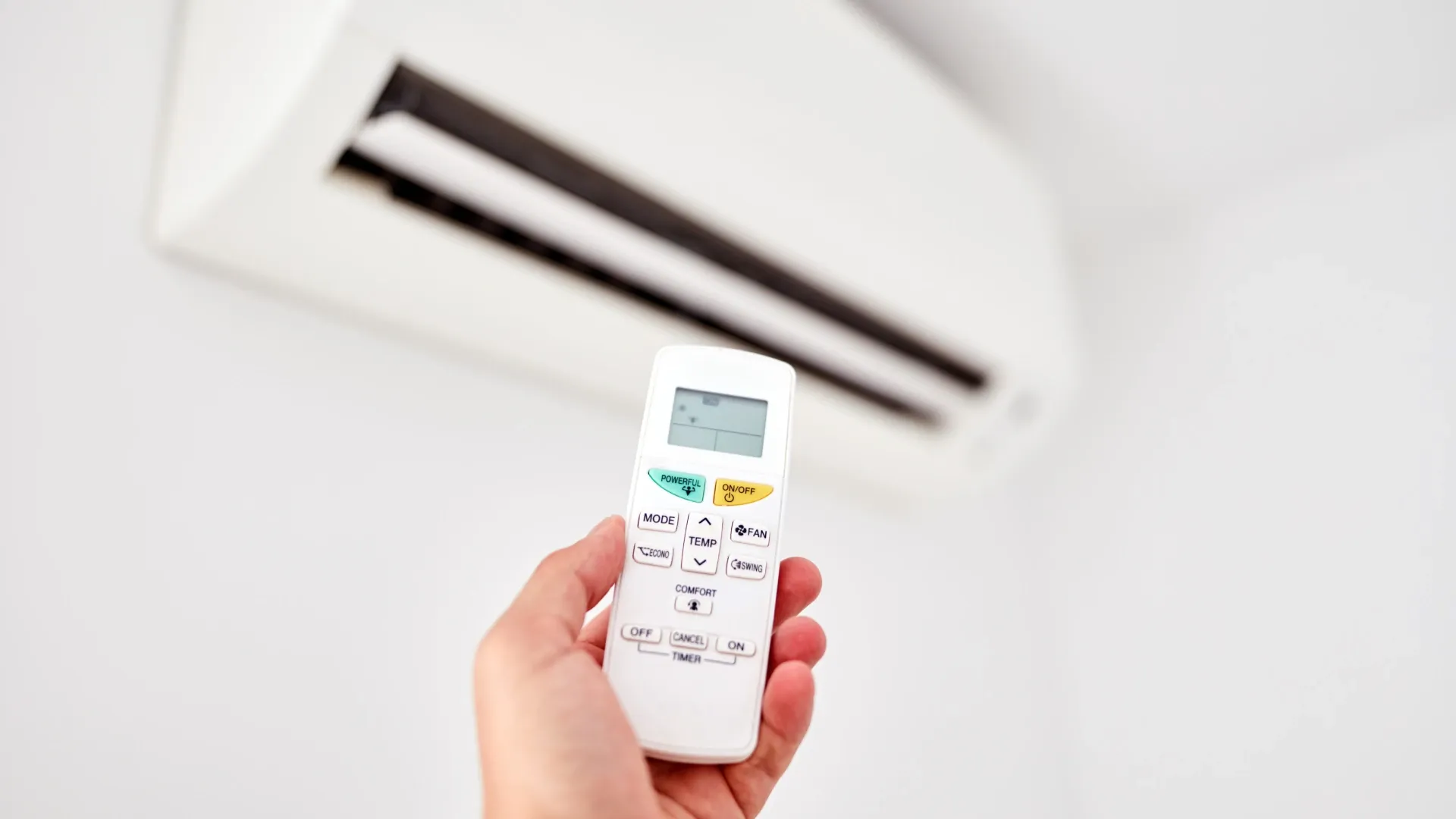 Imagem de uma pessoa apontando um controle de ar-condicionado para o aparelho  