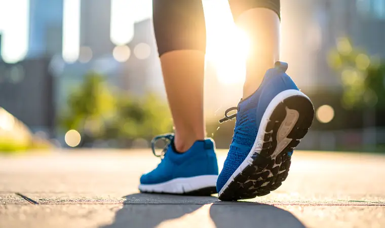 Tênis azul no pé de uma pessoa caminhando em um parque.