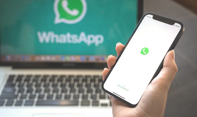 Imagem mostra uma pessoa segurando um celular. Na tela aparece o logo do WhatsApp
