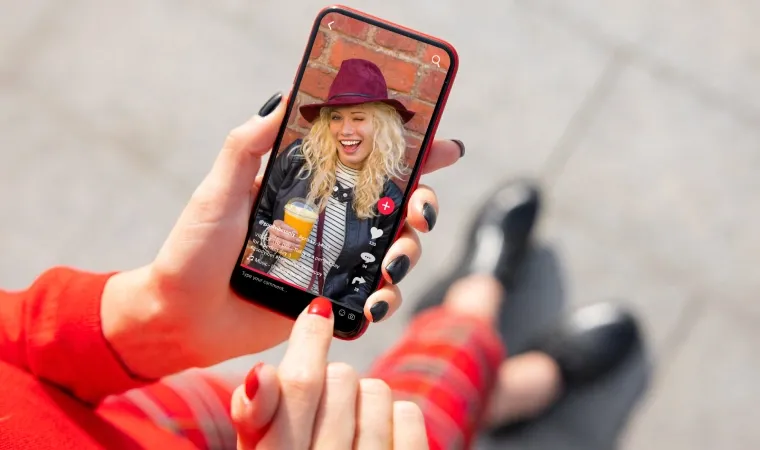 Mão de mulher segurando um celular com um vídeo do TikTok aberto