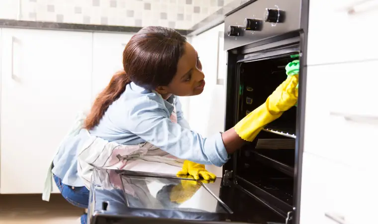 mulher tirando a gordura de um fogão