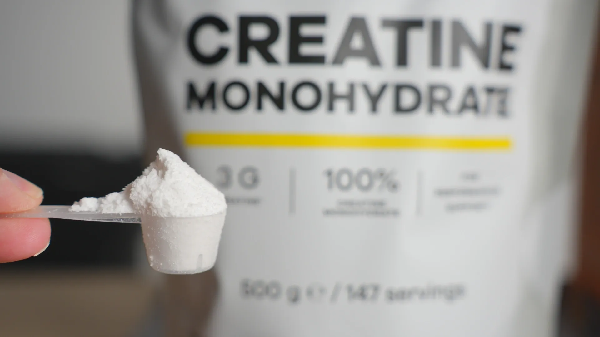 Scoop de creatina na frente de uma embalagem de creatina monohidratada
