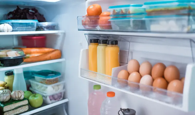 Alimentos dentro de uma geladeira pequena com a porta aberta