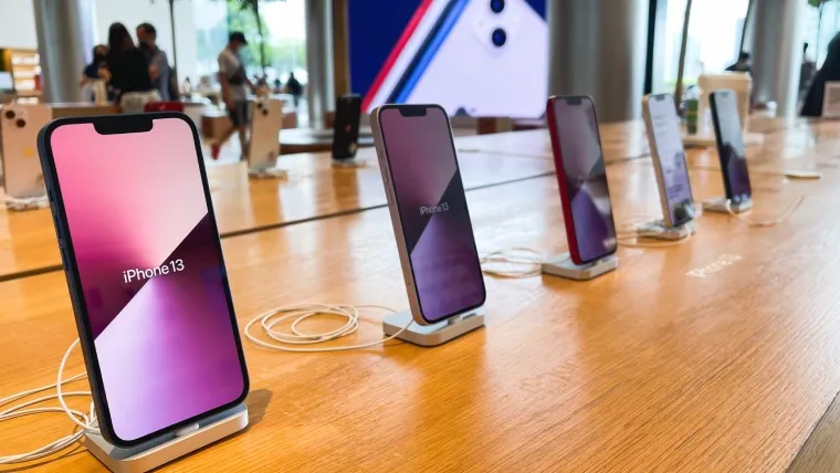 Imagem de uma bancada com vários modelos de iPhone 13  