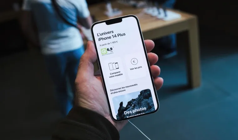 Um iPhone 14 Plus está ligado na mão de uma pessoa