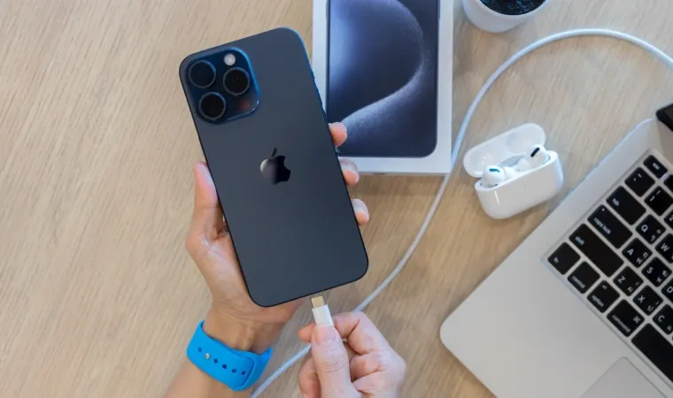Pessoa no escritório colocando o iPhone 15 Pro Max para carregar