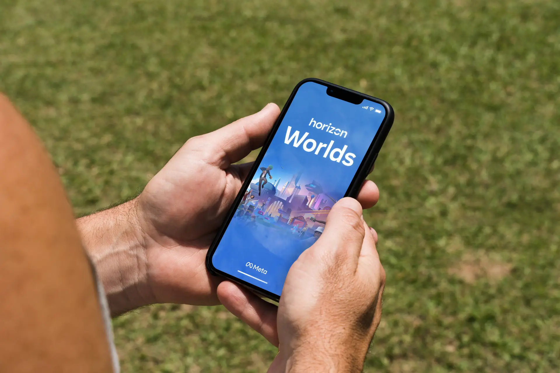 Uma pessoa segura um celular na vertical. Na tela aparece um game chamado Horizon Worlds