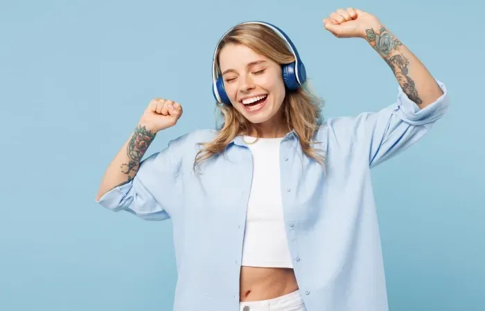 Mulher de camisa de botão azul ouvindo música com o seu headphone em fundo azul