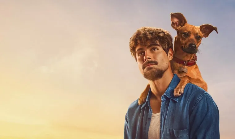 divulgação do filme Caramelo, mostrando o ator Rafael Vitti olhando para o horizonte com um cachorro caramelo apoiado em seus ombros.
