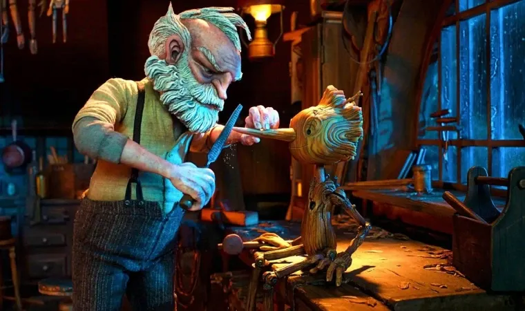 Cena do filme Pinóquio de Guillermo del Toro, mostrando Gepeto esculpindo um boneco de madeira em um ateliê iluminado.