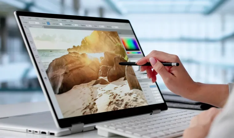 Imagem de uma pessoa usando uma caneta para editar foto em um notebook 2 em 1 com a tela touchscreen