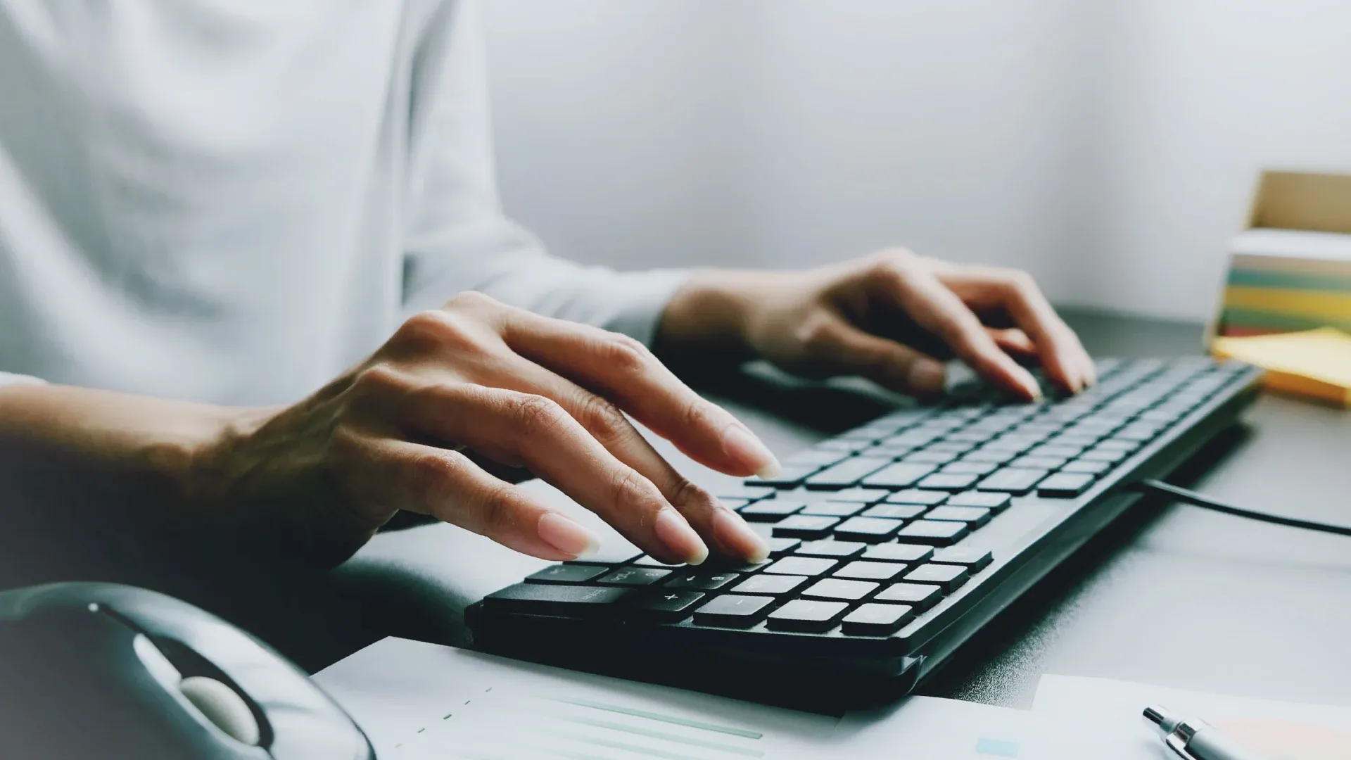 mesa de trabalho, mãos de mulher digitam em teclado