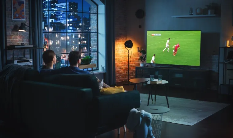 Casal assiste a um jogo de futebol na TV em uma sala aconchegante