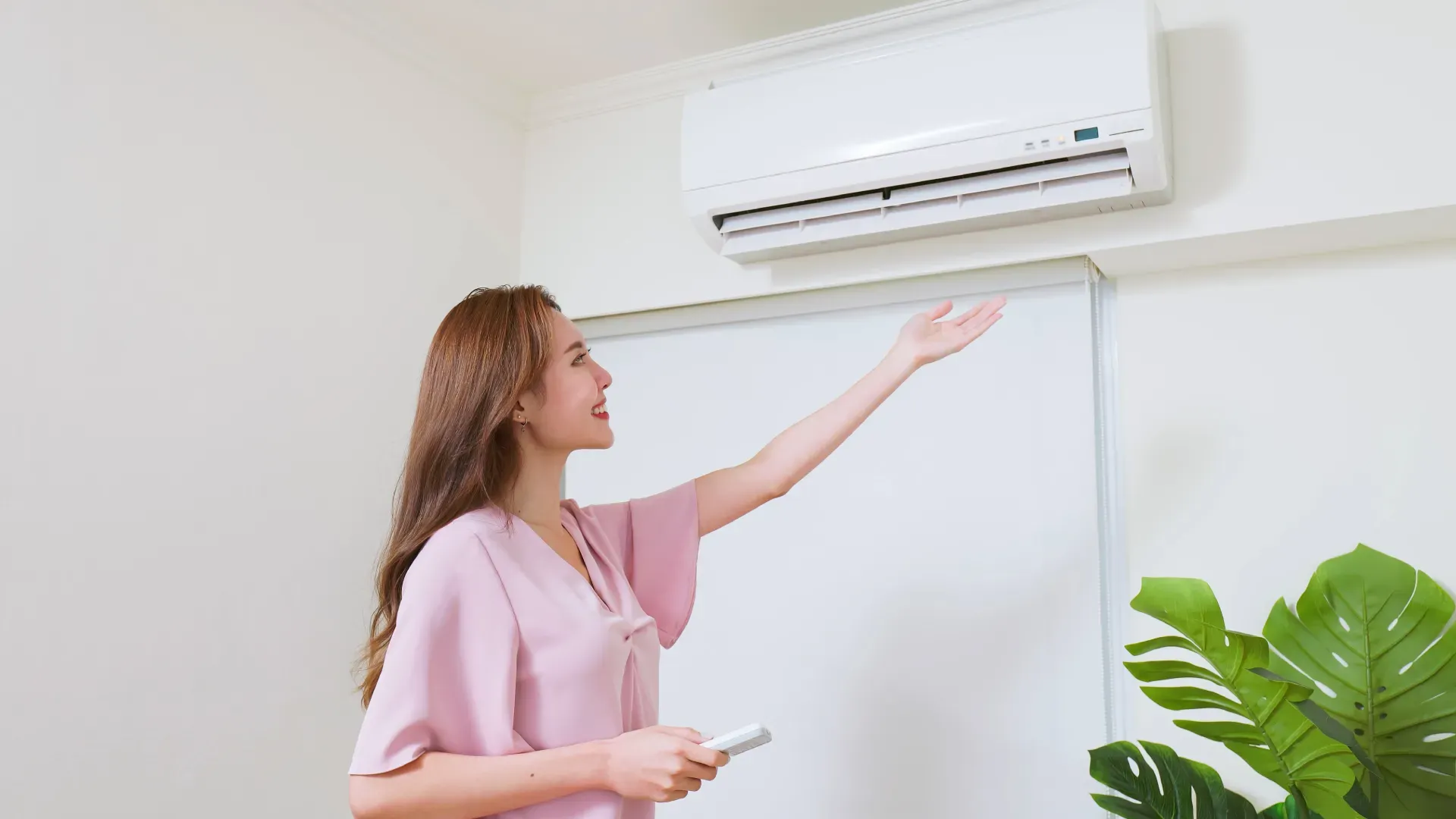 Jovem mulher com a mão estendida sentindo o vento do ar-condicionado