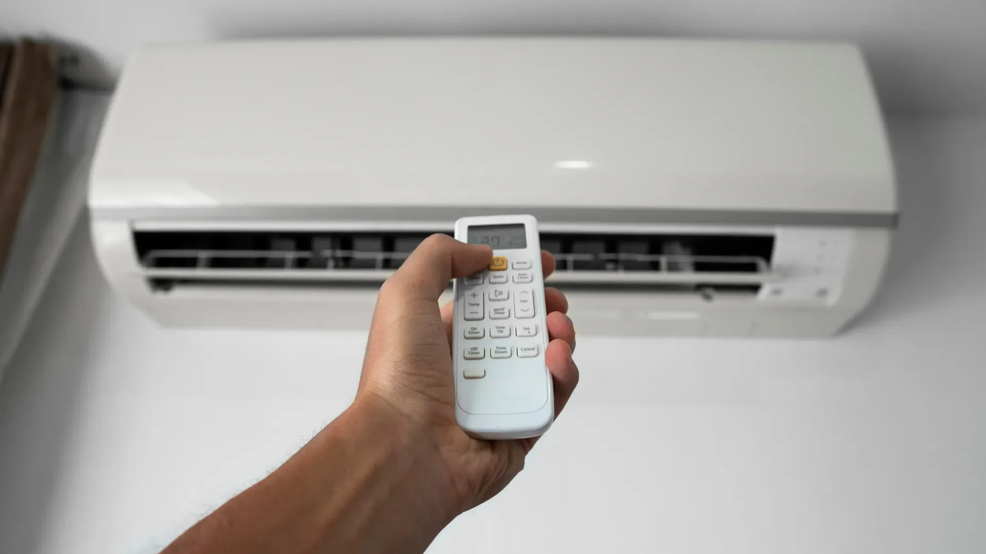 Técnico apontando para um ar-condicionado depois de ter consertado o aparelho 