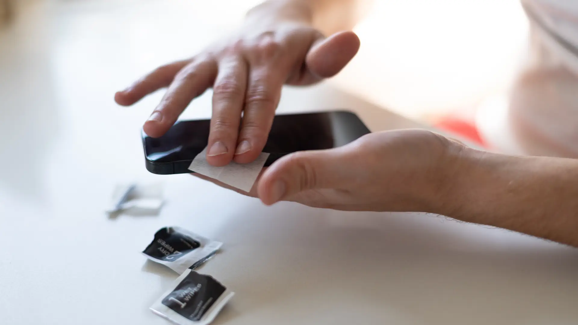Técnico limpando a tela para aplicar a película de cerâmica no celular