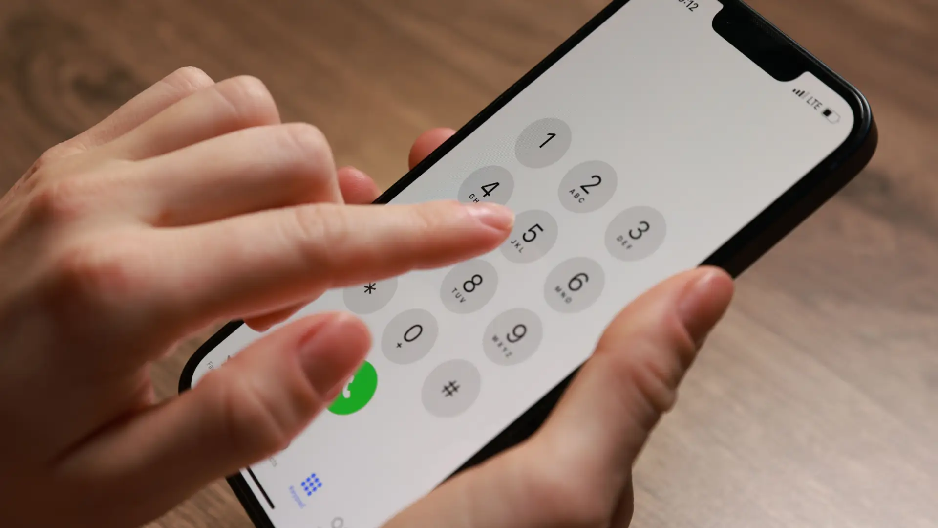 Uma pessoa está com o celular ligado. Na imagem aparece o teclado numérico