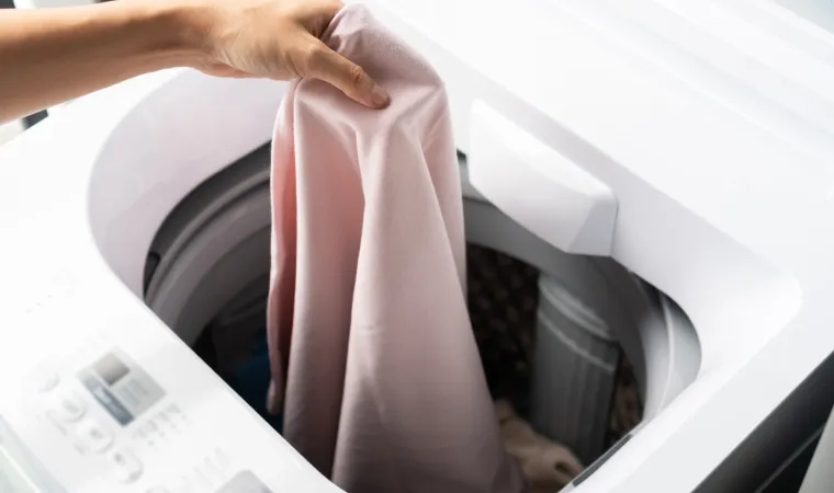 Mulher colocando lençol dentro da máquina de lavar Electrolux 15 kg LEC15