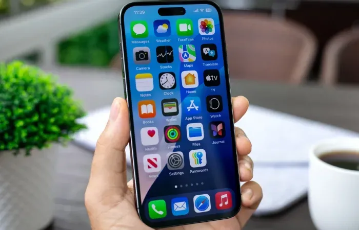 Imagem de uma mão segurando um iPhone grande com a tela ligada
