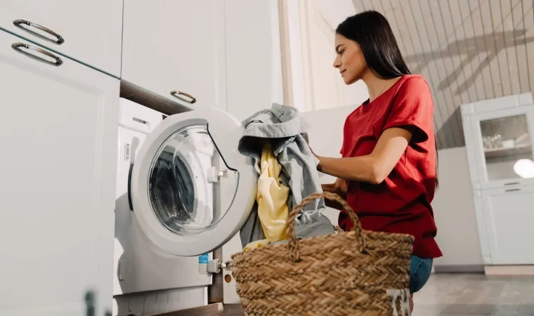 Mulher recolhendo roupas na máquina de lavar