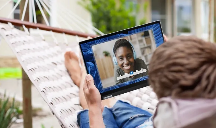Imagem mostra uma pessoa deitada em uma rede utilizando um notebook 2 em 1 com IA da Dell.