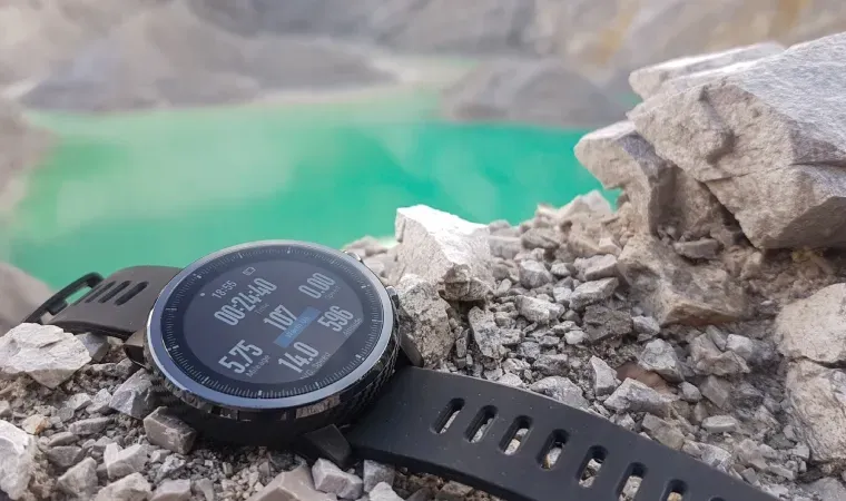 Imagem de um smartwatch Amazfit em cima de algumas pedras, e ao fundo um lago com cor esverdeada 