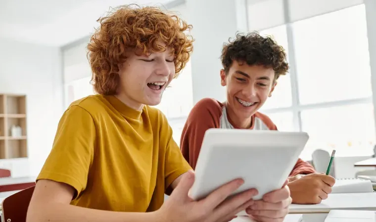 Imagem de duas crianças olhando para um tablet enquanto estudam