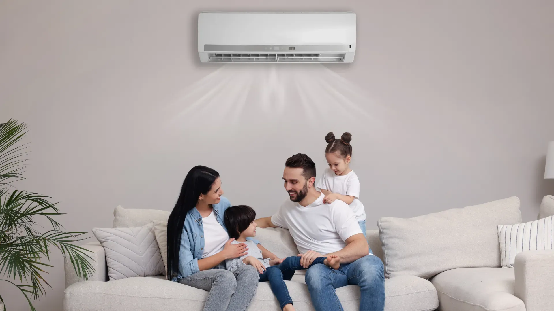 Família sentada em um sofá, com um ar-condicionado Split ventilando ar em sua direção.