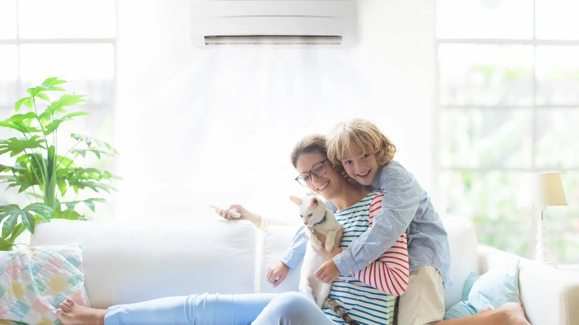 Mãe, filho e gato sentados no sofá da casa aproveitando o ar-condicionado