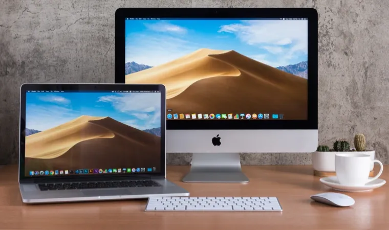 Imagem de um Macbook e um iMac, ambos com a mesma tela de área de trabalho do macOS 