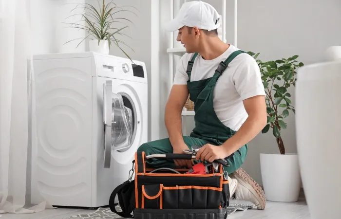 Imagem de uma pessoa fazendo um conserto em uma máquina lava e seca